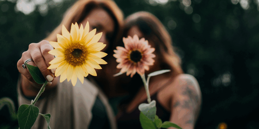 Des femmes brandissant un tournesol, symbole de lumière, d’espoir et de solidarité, illustrant la force collective et le soutien mutuel dans le parcours de guérison et de coaching féminin après un cancer