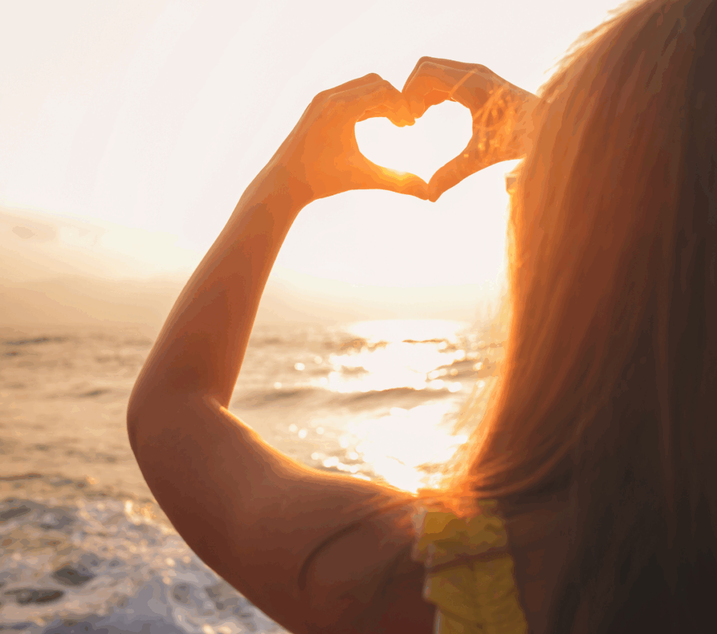 Femme formant un cœur avec ses mains, image d’amour de soi, bienveillance et connexion émotionnelle, reflet du coaching féminin axé sur l’estime de soi et le soutien après un cancer