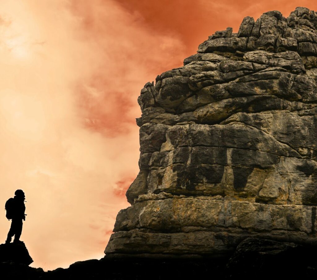 Femme en bas d’une falaise, symbolisant le défi, la prise de conscience et le début d’un chemin de transformation, métaphore du parcours de résilience et de coaching féminin après un cancer